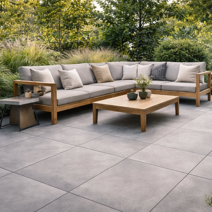 Tuin met grootformaat grijze keramische buitentegels en houten loungeset met kussens